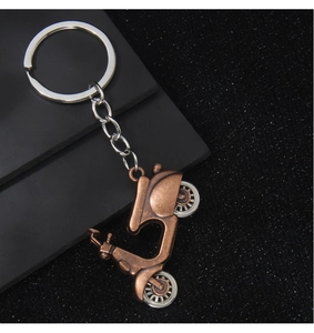 Macro shot of a vintage bronze motorcycle pendant keychain on a sleek black surface