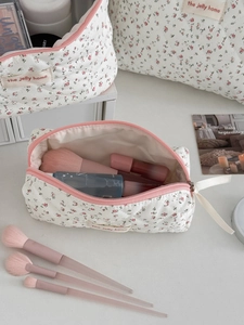 Gros plan sur la trousse à maquillage matelassée fleurie avec logo et fermeture éclair rose