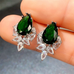Close-up of pear-shaped green gemstone earrings with marquise zircon stones held by hand