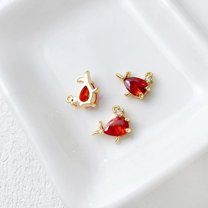 Detailed macro view of three gold dolphin pendants with red pear-shaped gemstones
