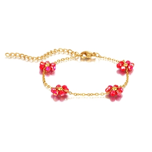 Detail view of gold stainless steel chain with red floral glass beads on white background