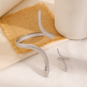 Macro detail of silver snake jewelry set with intricate scale texture on white fabric