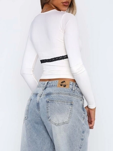 Détail du haut blanc à manches longues avec dentelle noire au dos et jean bleu