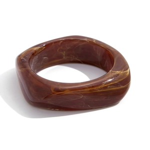 Dettaglio di un bracciale largo irregolare in resina con trama ambrata vintage