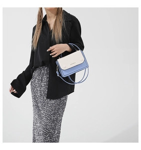 Detail of light blue and cream contrast panel shoulder bag with top handle and strap