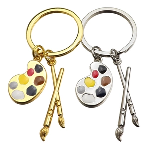 Artistic palette and paintbrush keychains in gold and silver finishes for art lovers