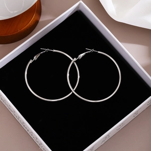 Macro shot of silver large hoop earrings with clasp on black velvet jewelry box lining