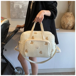 Vue détaillée du sac à langer matelassé avec broderie d'ours et sangles réglables