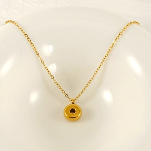 Minimalist golden bubble initial necklace with a round donut pendant on a fine chain