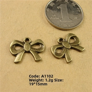 Zinc alloy bow pendants in antique bronze finish with size reference next to a coin