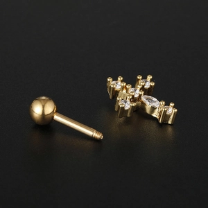 Macro shot of gold stainless steel cross piercing earring with white cubic zirconia crystals