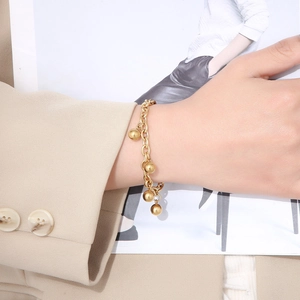 Detailed view of a gold-plated stainless steel bead bracelet worn on a woman's wrist