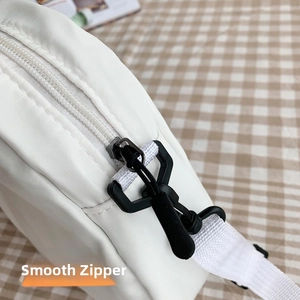 Détail du zip noir fluide sur une sacoche bandoulière en nylon blanc avec sangle tissée
