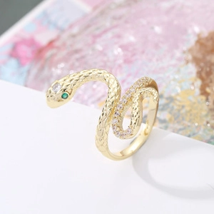 Macro detail of gold snake ring featuring green zircon eyes and micro-pave white stones