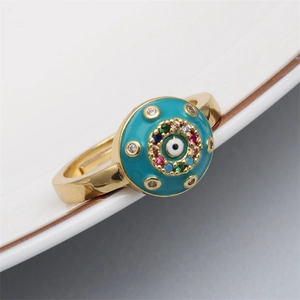 Detail of gold evil eye ring with turquoise enamel and colorful zircons on white ceramic