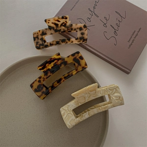 Three acetate hair claws in tortoiseshell and marble patterns on a white desk