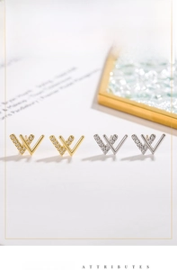 Macro detail of gold and silver W-shaped stud earrings with micro-inlaid zircons