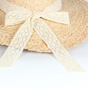 Straw sun hat with wide brim and white lace ribbon bow for summer beach vacation
