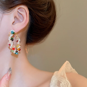 Detail of colorful beaded hoop earrings with white pearls on a female model