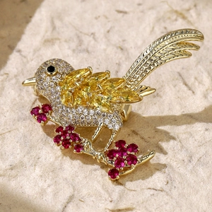 Macro detail of bird brooch with golden zircon feathers and red floral crystal accents