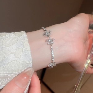 Detail of silver flower bracelet with sparkling zircons on a model wrist closeup