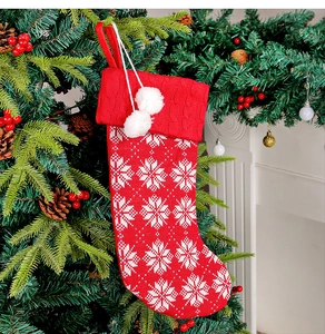 Close-up of a red knitted Christmas stocking with white snowflake patterns and pompoms