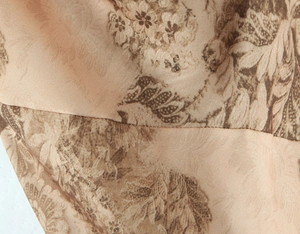 Close-up of brown vintage floral print on smooth satin fabric with stitched seam detail