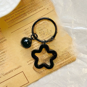 Macro shot of a black star keychain with bell on vintage newspaper background