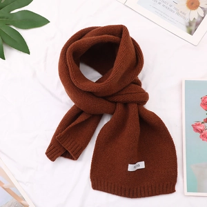 Close-up of a warm brown knitted scarf with a minimalist white fabric label detail