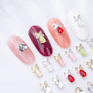 Macro shot of 3D bow-knot nail charms with colorful teardrop rhinestones on white background