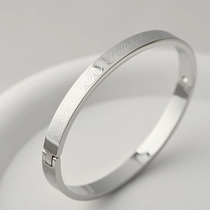 Macro shot of polished silver bangle featuring intricate wave pattern and side hinge detail
