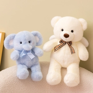 Plush teddy bear and elephant toys with plaid bows and angel wings on a soft chair