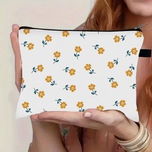 Florale Kosmetiktasche mit gelben Blumen und schwarzem Reißverschluss in der Hand