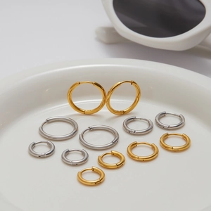 Ensemble créoles en acier inoxydable or et argent dans un plat en céramique blanc