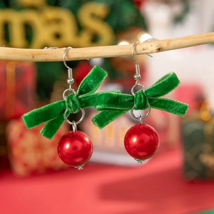 Boucles d'oreilles de Noël avec nœud en velours vert et perle rouge sur une branche en bois