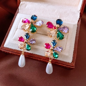 Gros plan sur boucles d'oreilles fleur 18k avec pierres colorées et pendentifs perles