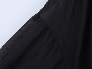 Detail of elegant black dress showing sheer sleeve seam and textured fabric stitching