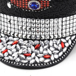 Close-up of luxury black sequin hat with rhinestones, silver studs and central blue gem