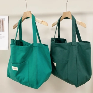 Detail of green striped canvas tote bag with functional front pocket and logo