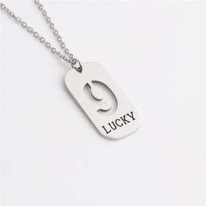 Macro shot of silver titanium steel tag pendant with hollow number 9 and LUCKY engraving