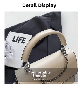 Detail of a beige leather handbag featuring a silver metal chain and thick padded handle