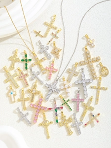 Detailed flat lay of various iced out cross pendants with cubic zirconia and colored gems