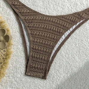 Detail of brown smocked bikini bottoms with textured wavy fabric on faux fur background