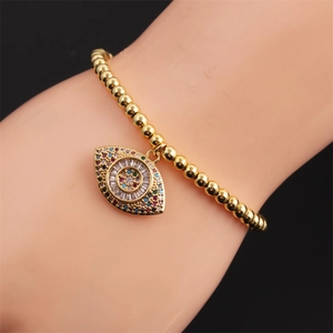 Detail of gold evil eye charm bracelet with micro-paved zircons and stretch beads