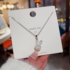 Detailed close-up of a silver spinning rabbit necklace with zircon stones and white inlay
