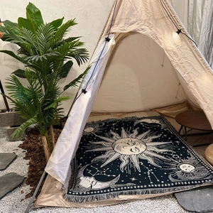 Detail of bohemian sun and moon woven blanket with white fringe edges in camping setting