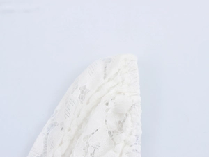 Close-up of delicate white lace fabric with floral patterns on the mini dress sleeve