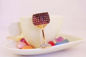 Detail of crystal wine glass keychain with purple rhinestones on a warm heart tray