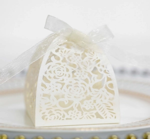 Detailed laser-cut white wedding favor box with floral patterns and a satin ribbon bow