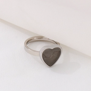 Polished heart-shaped stainless steel ring with gray gemstone inlay on white fabric